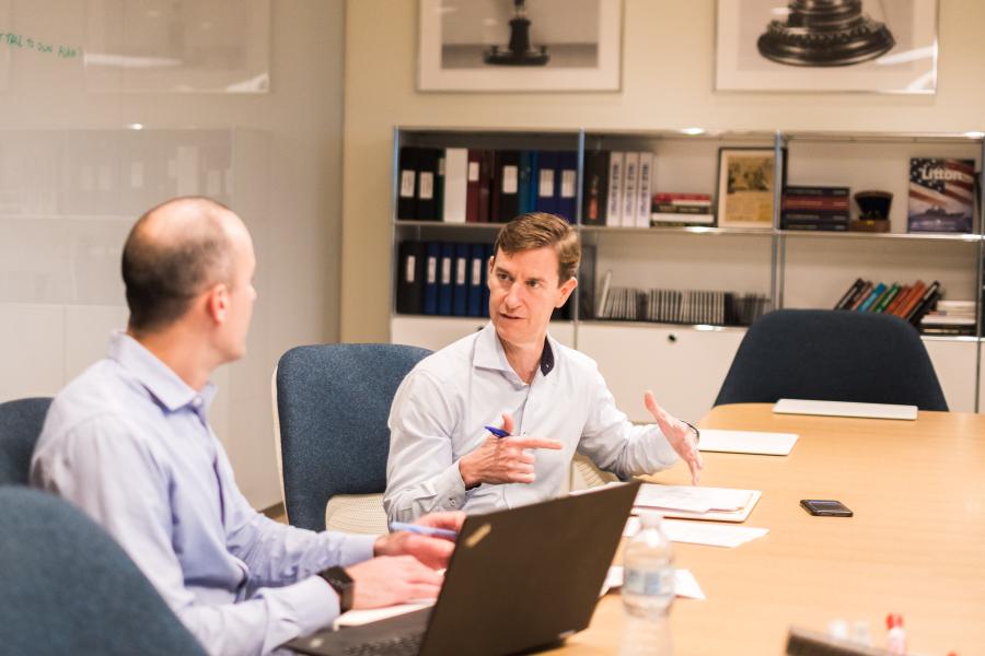 two men speaking at a conference room table